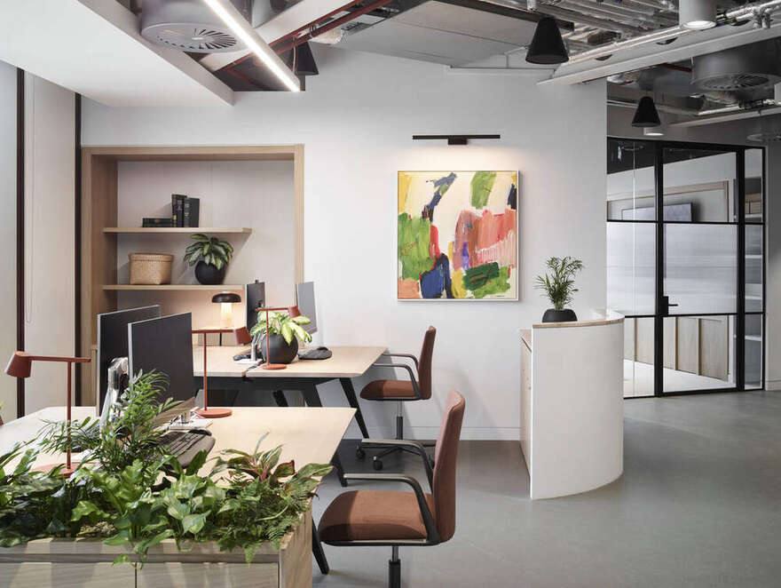 Desks with planted troughs and an abstract painting on the wall