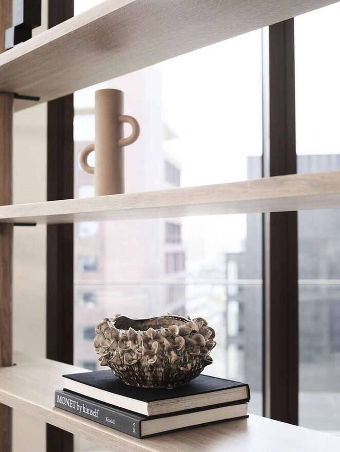 Ceramic vessel styled on oak shelving against the city